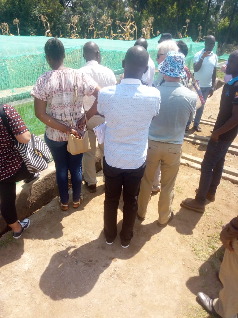 Group beside netted aquaculture ponds in the Nyanza Gulf region